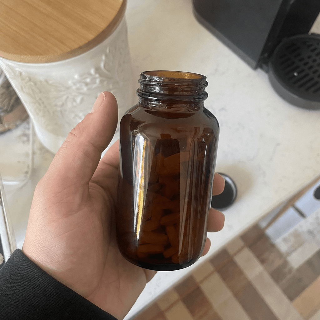 Hand holding a Rooted amber bottle against a bright kitchen background — authentic customer photo